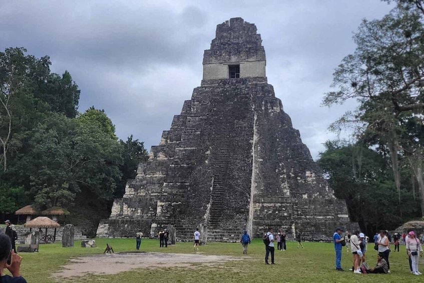 A large ancient pyramid with tourists around it. 2
