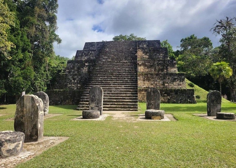 A pyramid structure with a staircase leading up to it, surrounded by grassy areas and large stone slabs. 1