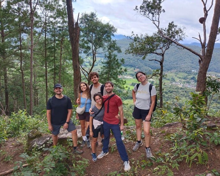 A group of people standing on a forested hill with a view of a valley. 4