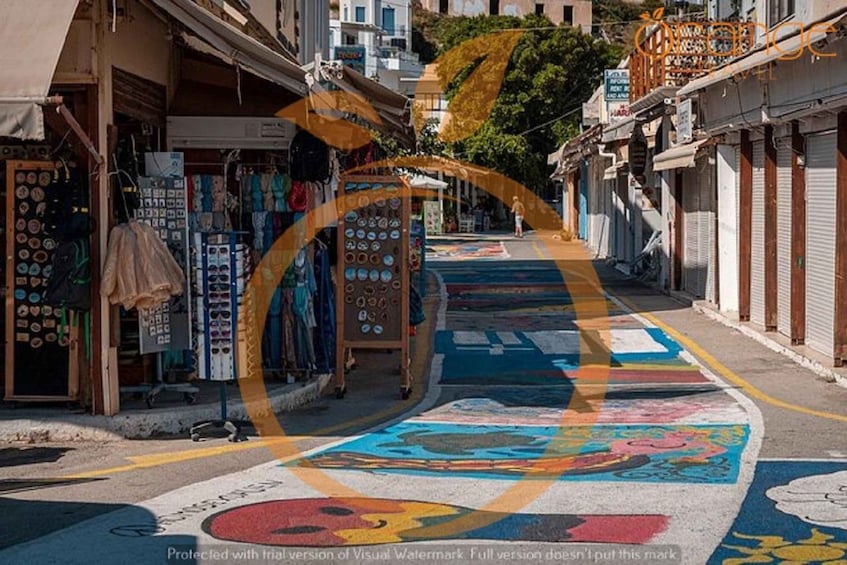 A street with colorful pavement art and shops on either side. 1