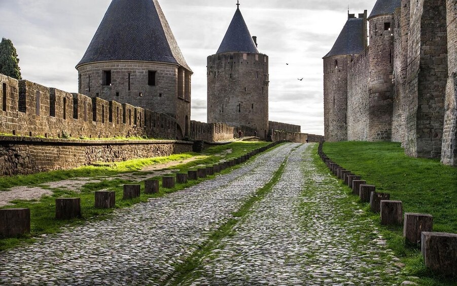 A cobblestone pathway flanked by historic stone walls and towers. 4