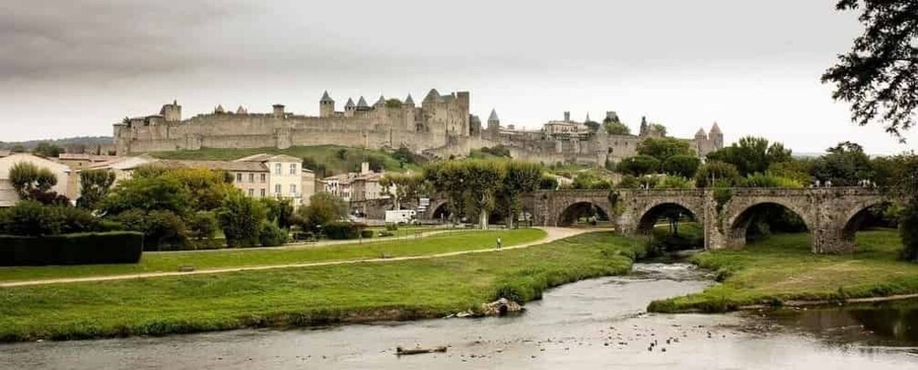 A castle on a hill, a bridge over a river, and a grassy area with trees. 5