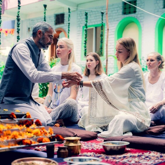 A group of people sitting on the floor in a room decorated with hanging garlands. 5