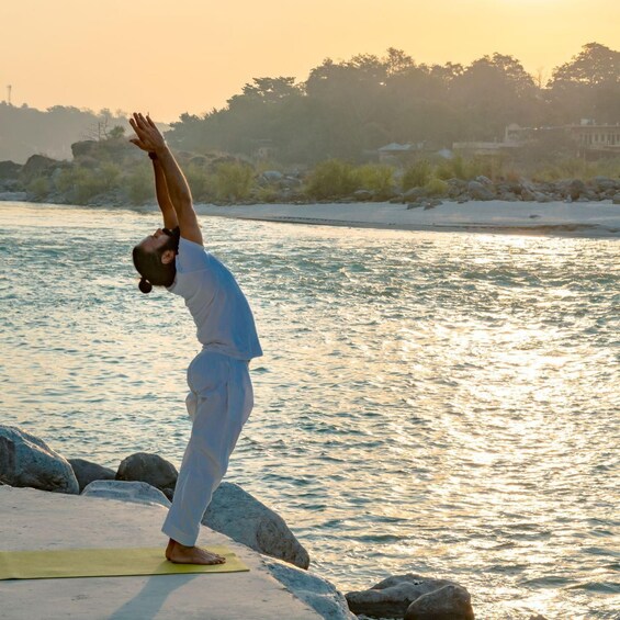 A person performing a yoga pose on a mat by a river. 1