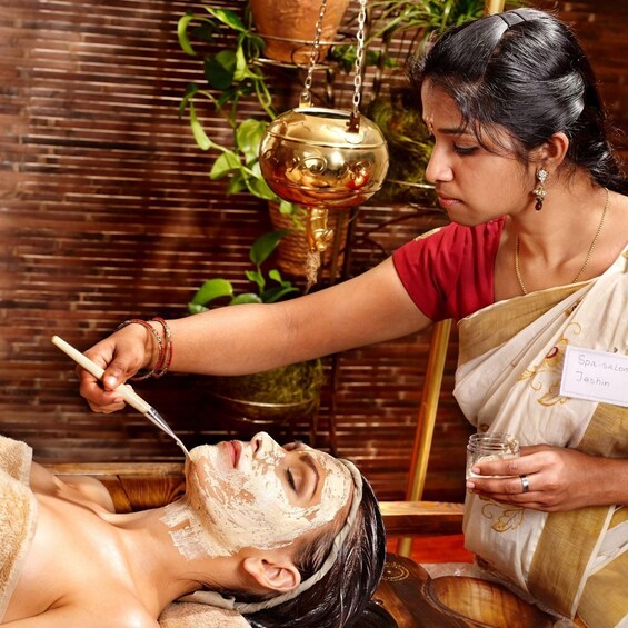 A person receiving a facial treatment, with a bowl of liquid and a spoon in the background. 4