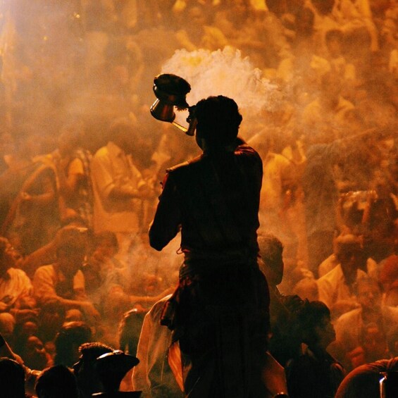 A person playing a traditional wind instrument in a crowded, dimly lit setting. 3
