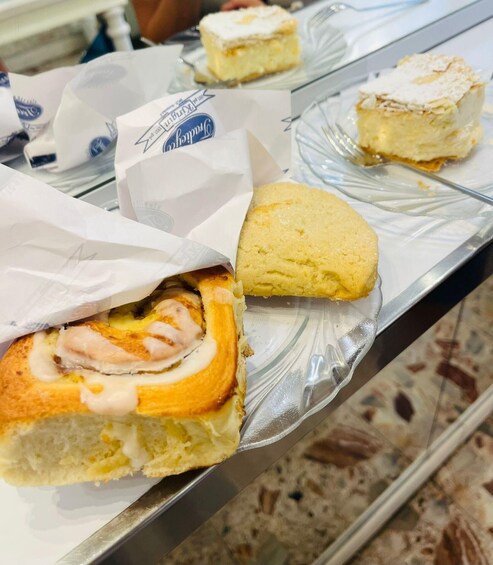 A pastry with a swirl of cream and a piece of fruit on top, placed on a reflective surface. 1