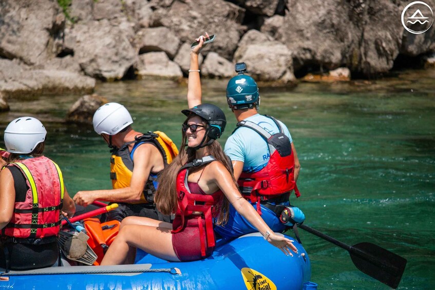 A group of people rafting on a river with rocky banks. 3