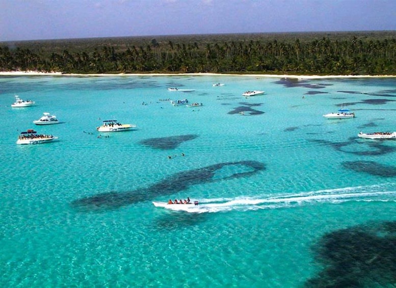 A turquoise sea with boats and a forested coastline. 4