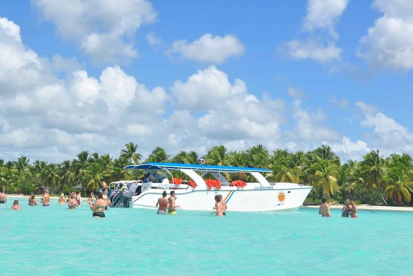 A boat named 'LA BRIANNA' docked at a beach with people swimming in the water and palm trees in the background. 2