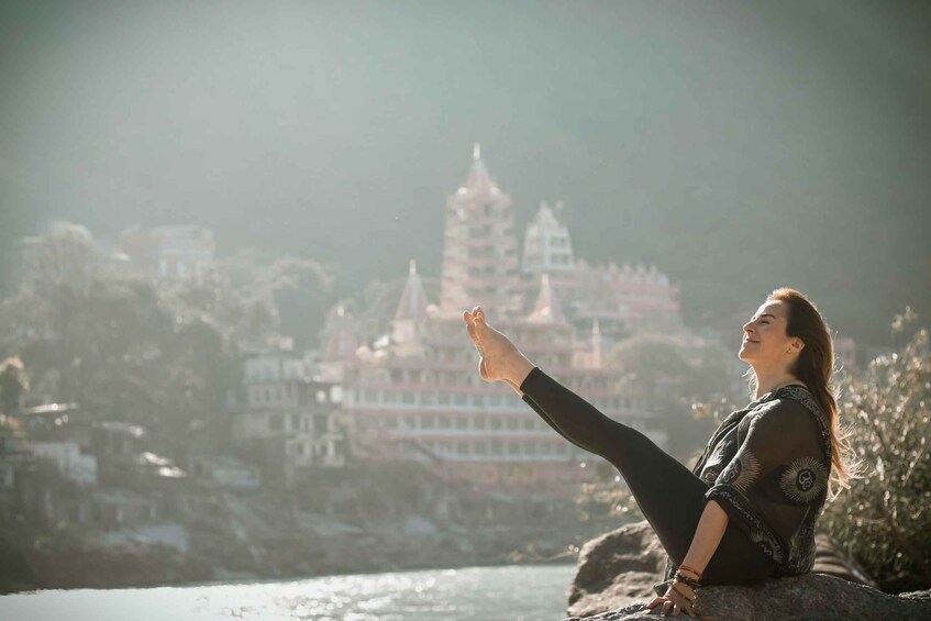 A person sitting on a rock with a temple in the background. 2