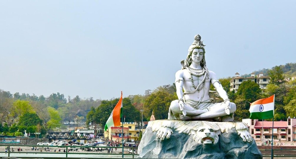 A seated statue of a deity on a rock, with two flags in the background. 5