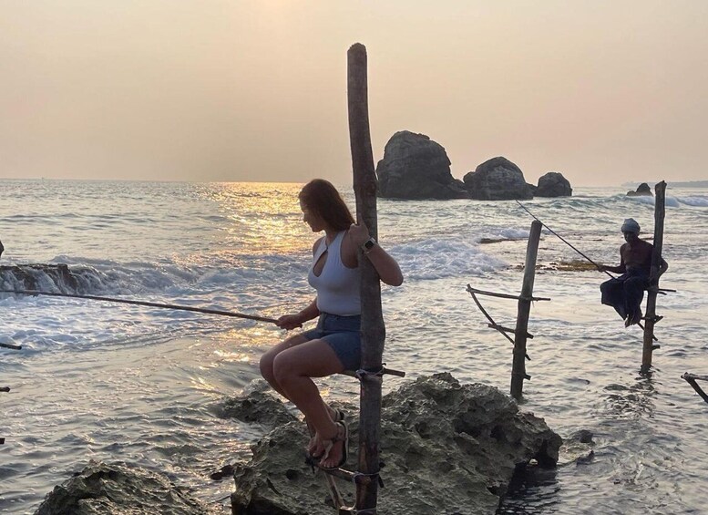 A person fishing by the sea with rocky formations in the background. 3