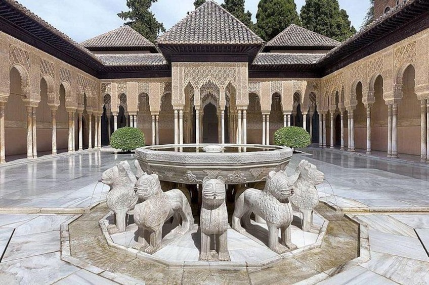 A courtyard with a fountain surrounded by stone lions, arches, and tiled roofs. 1