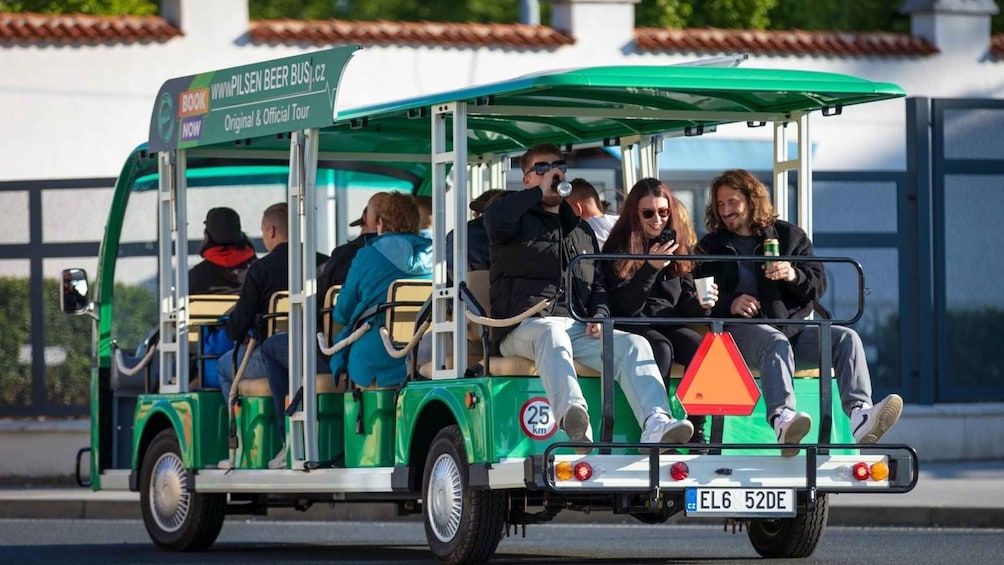 A green tour bus with passengers, a speed limit sign, and a license plate. 5
