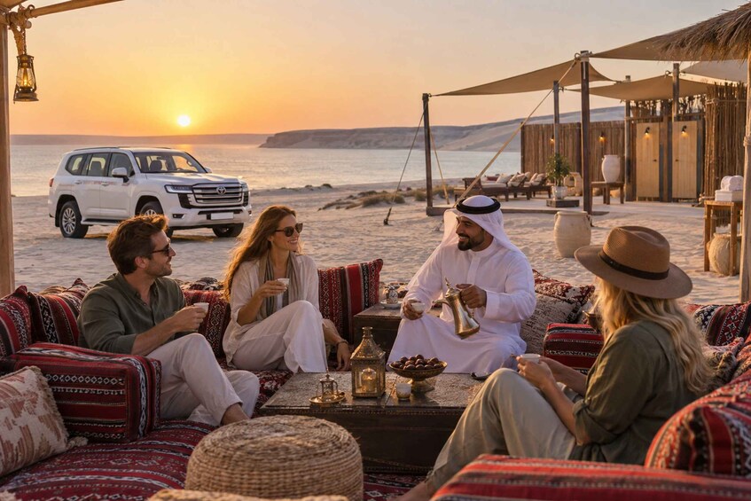 A group of people sitting on patterned cushions on a beach, with a white SUV parked nearby and a sunset in the background. 5