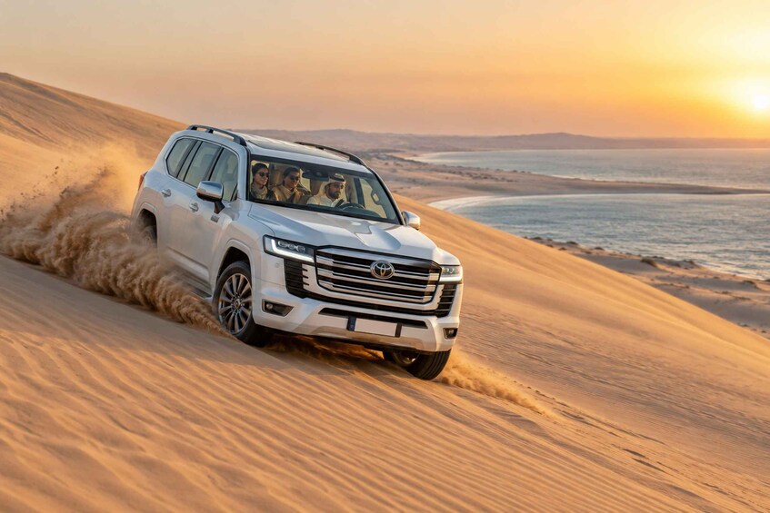 A white SUV driving through sand dunes with a sunset in the background. 5