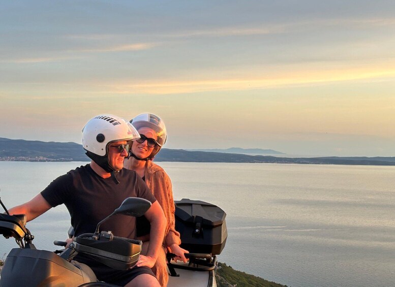 Two people on a scooter overlooking a body of water with distant hills. 5