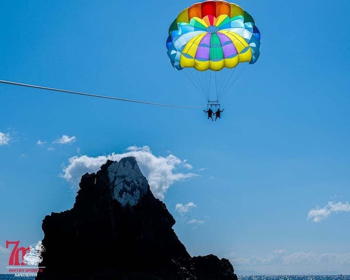 A person parasailing over a rocky coastline. 1