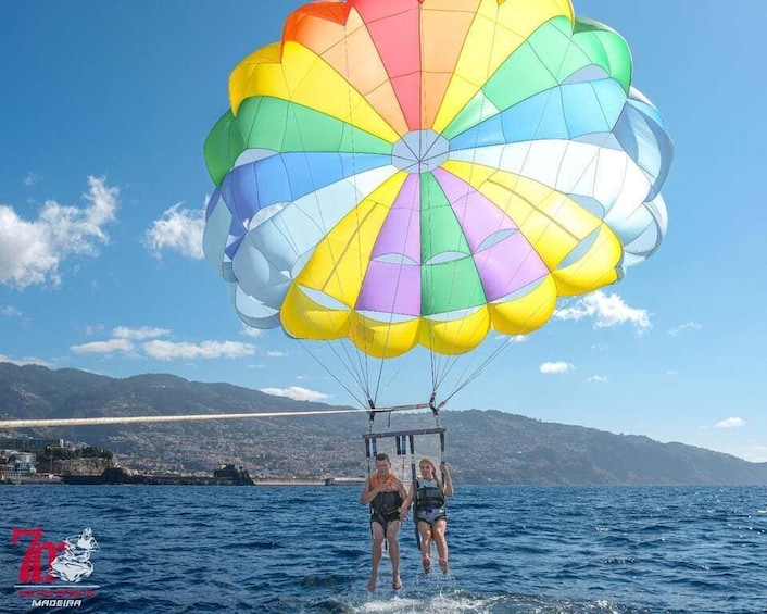 Two people parasailing over water with a colorful parachute. 3