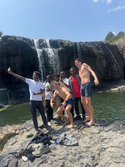 Un groupe de personnes se tient sur des rochers, près d’une cascade. 5