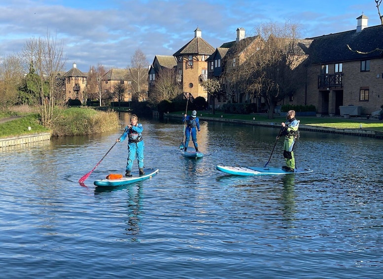 Three people paddleboarding on a calm river. 1
