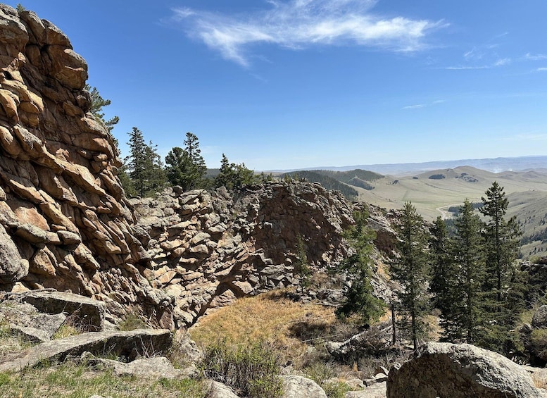 A rocky mountain landscape with sparse trees and a clear sky. 4