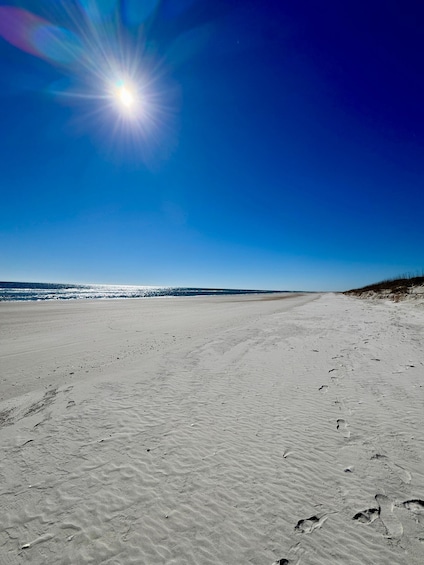A sandy beach with footprints and a clear blue sky. 1