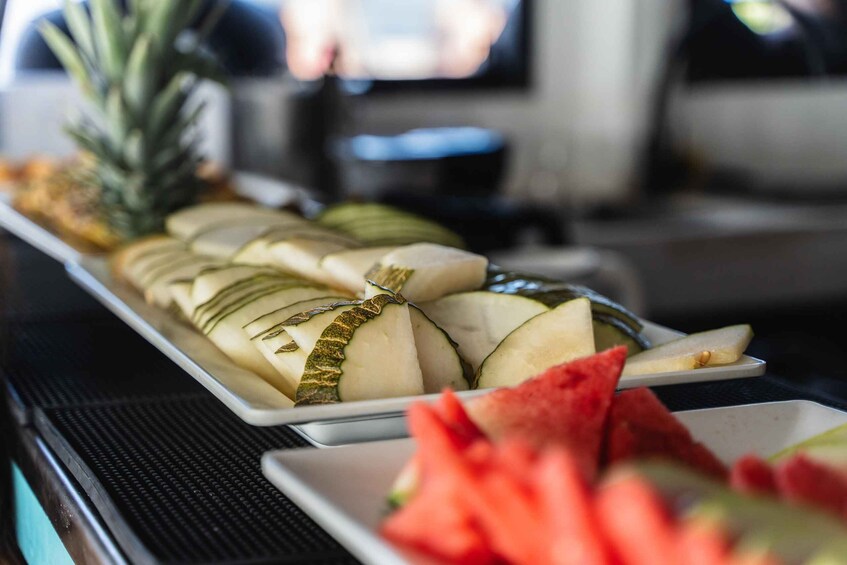 A tray of sliced fruits including pineapple, kiwi, and watermelon. 5