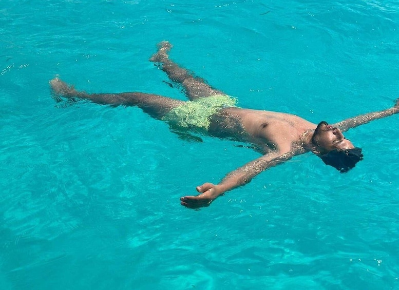 A person floating in clear blue water. 4
