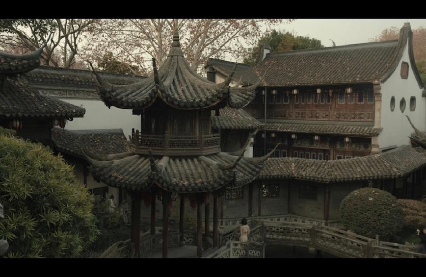 A traditional Chinese courtyard with ornate pagodas and a white building with wooden lattice windows. 5