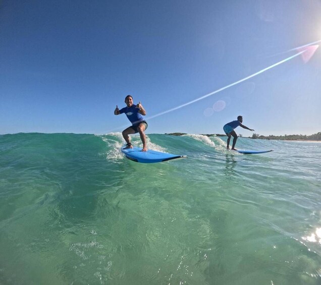 Two people surfing on blue boards in clear turquoise water. 2