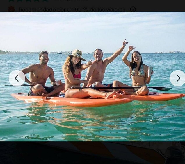 Four people sitting on a paddleboard in the water. 4