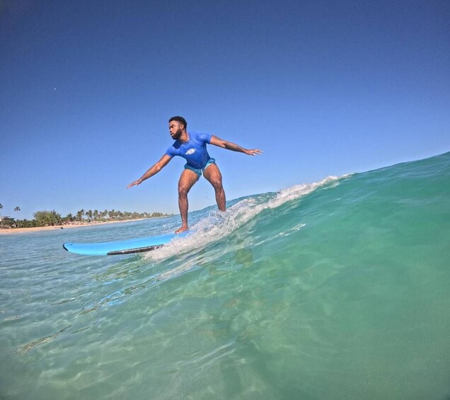 A person surfing on a clear blue ocean wave. 1