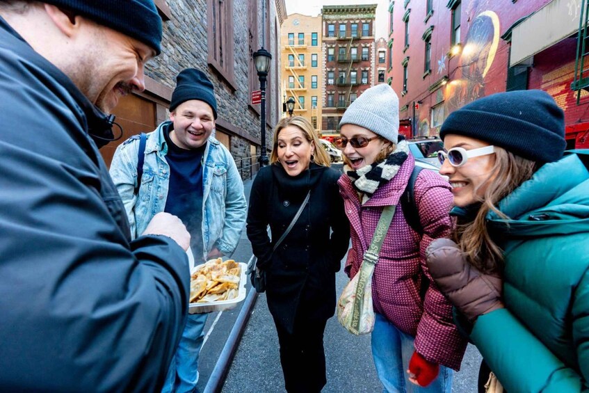 A group of people walking on a city street, some carrying food. 1