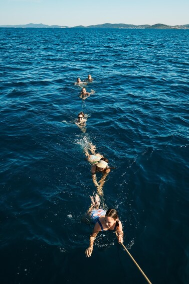 A group of people swimming in the ocean, with a clear view of the water and distant land. 3