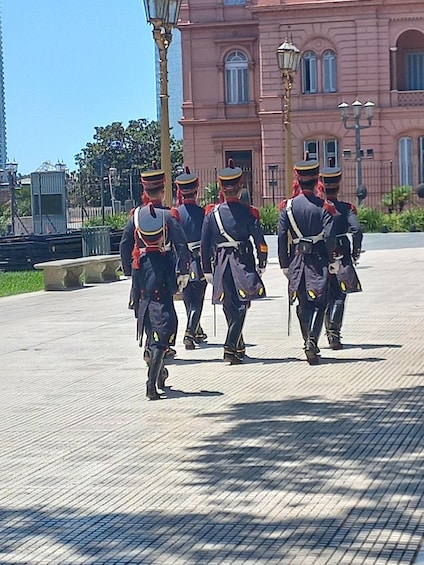 A group of uniformed guards walking in formation on a paved area. 2