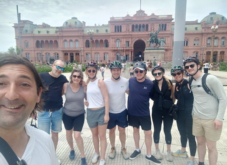 A group of people in front of a large pink building with domes and a statue. 4