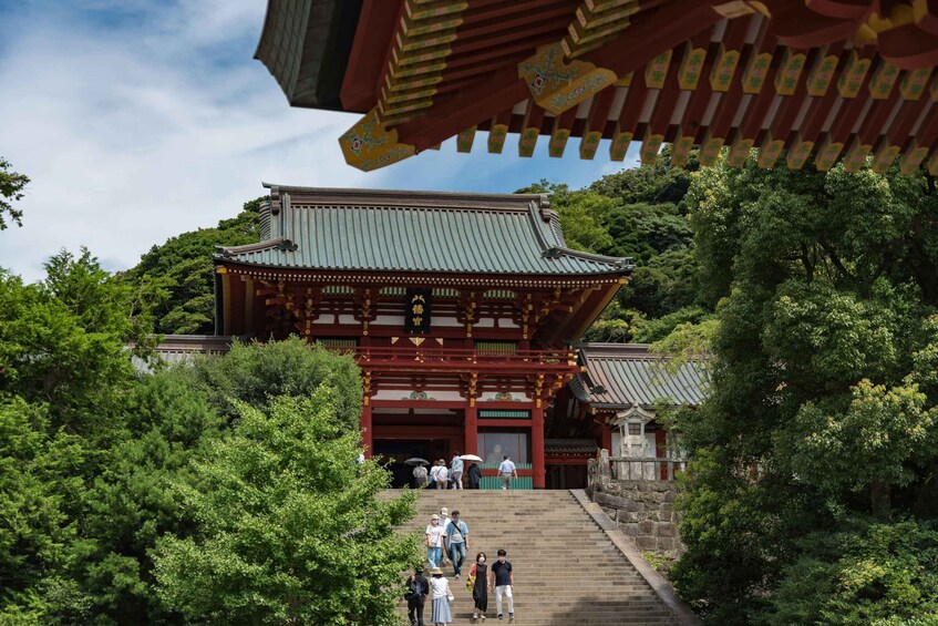 A traditional Japanese temple with a red and green roof, surrounded by lush greenery. 1