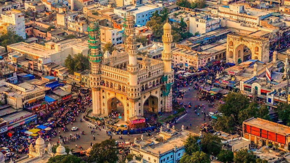 A bustling market area with a prominent historical building featuring domes and minarets. 1