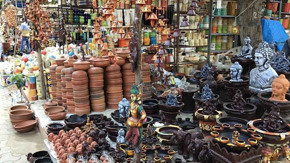 A market stall with various pottery items, including large terracotta pots, smaller bowls, and decorative statues. 2