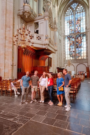 A group of people inside a church with a large organ and stained glass windows. 4