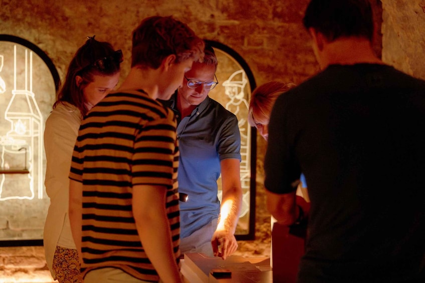 A group of people standing around a table with a lit-up display in the background. 5