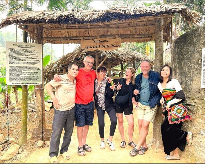 A group of people posing in front of a Thai ancient still house. 4