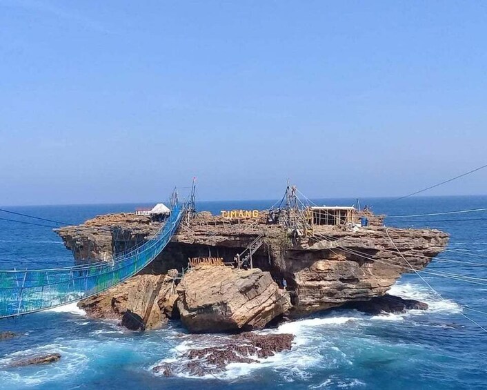 A rope bridge over a rocky island in the ocean. 5