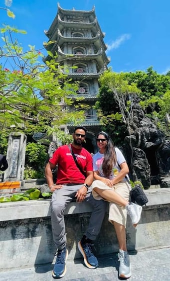 A couple sitting on a stone ledge with a traditional multi-tiered pagoda in the background. 5