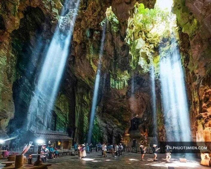 A cave with multiple waterfalls and a group of people. 1