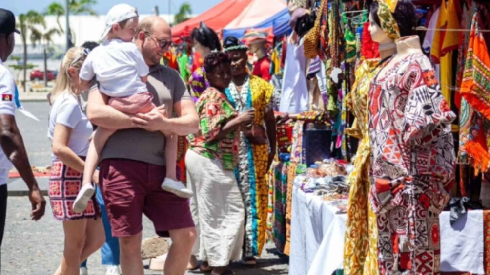 A market scene with people shopping and a child being held by an adult. 2