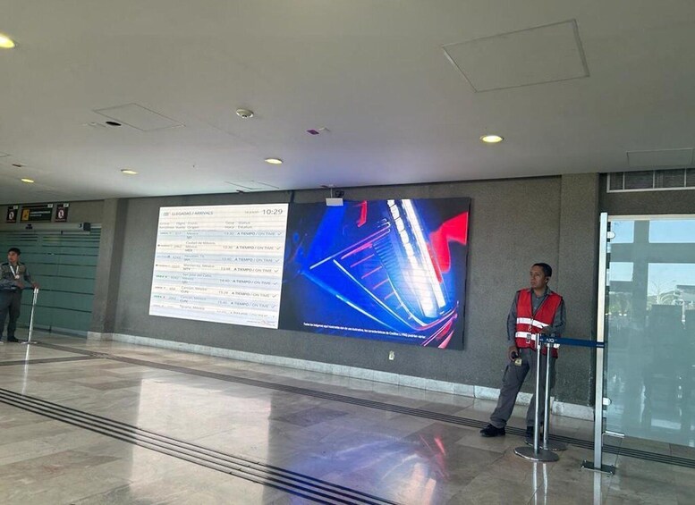 A modern airport interior with a digital flight information board and a security checkpoint. 4