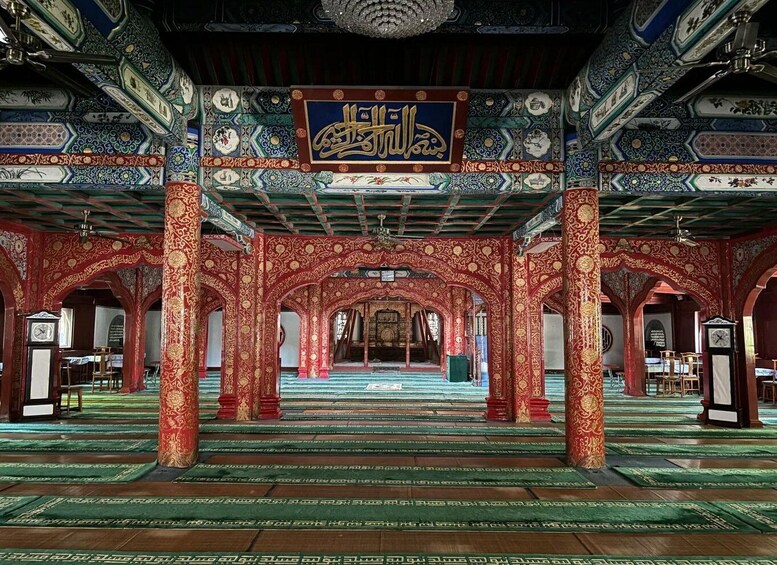 An ornate mosque interior with intricate tile work, red and gold patterns, and Arabic calligraphy. 2